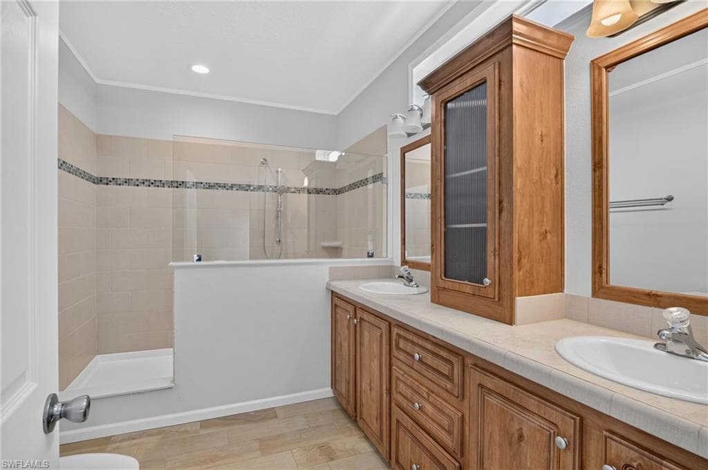 Owners Suite BathBath, featuring a dual vanity with light wood-finish cabinetry, a framed mirror, and an integrated countertop