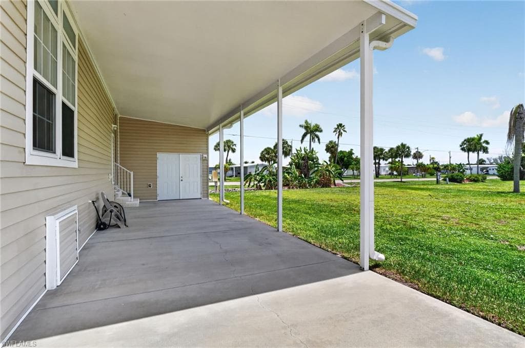 Expansive covered patio with concrete flooring, supported by white posts, and featuring a light-toned vinyl siding exterior