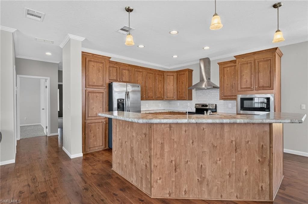 Open-concept kitchen featuring wood-finish flooring, a large island with a stone countertop, extensive wood cabinetry, stainless steel appliances, and pendant lighting