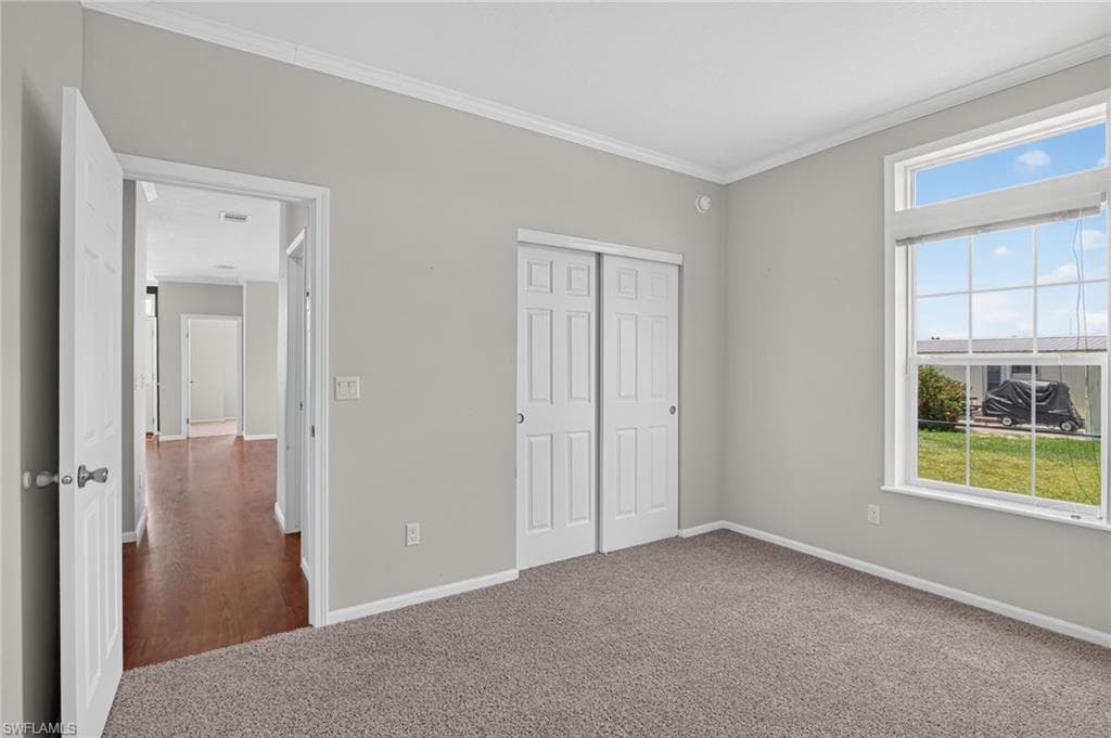 Bedroom 2, Bedroom featuring a large window with vertical blinds, neutral tone carpeting, double-panel sliding closet doors, and light gray wall paint