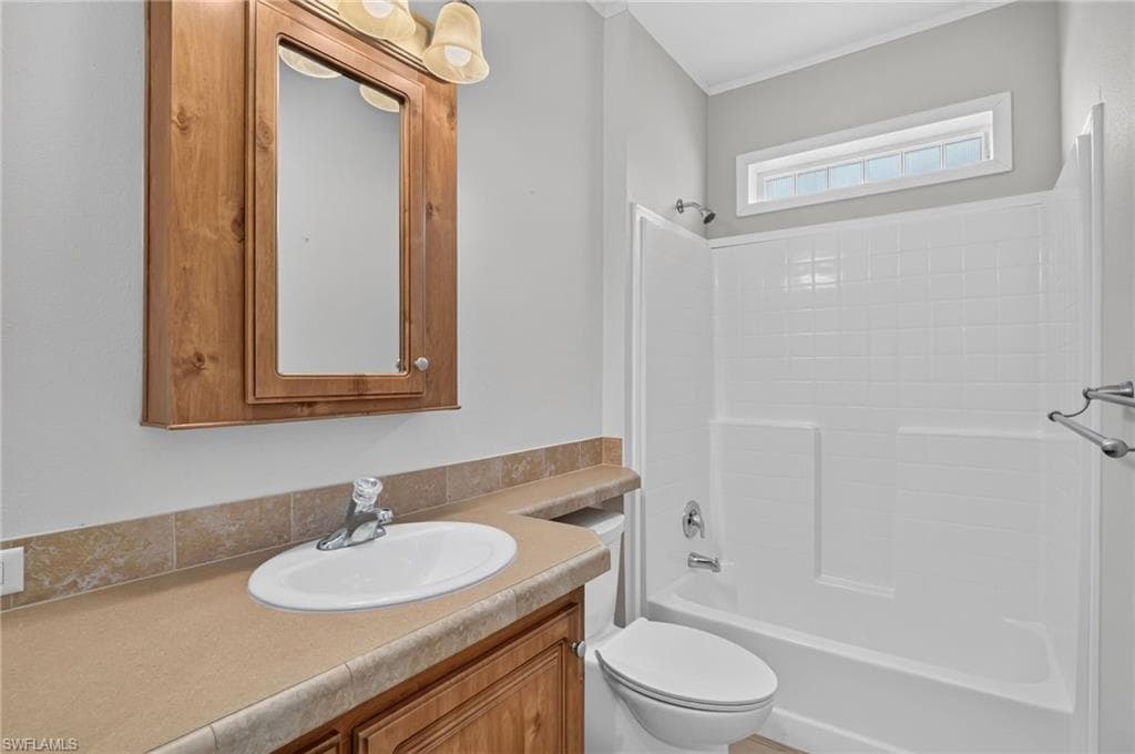 Main Bathroom featuring a wood-finish vanity with an integrated sink, a matching medicine cabinet, and a Main Bathroom with Shower and Tub, coordinated light fixture