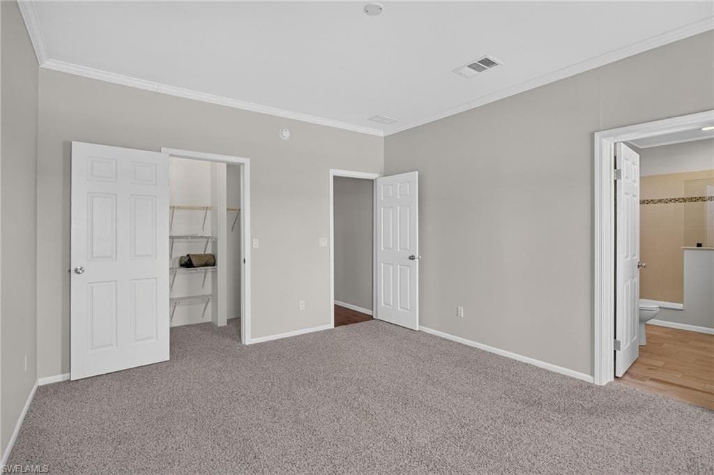 Owners Suite Walk In Closet. Room featuring grey carpeting, light grey walls, and white trim