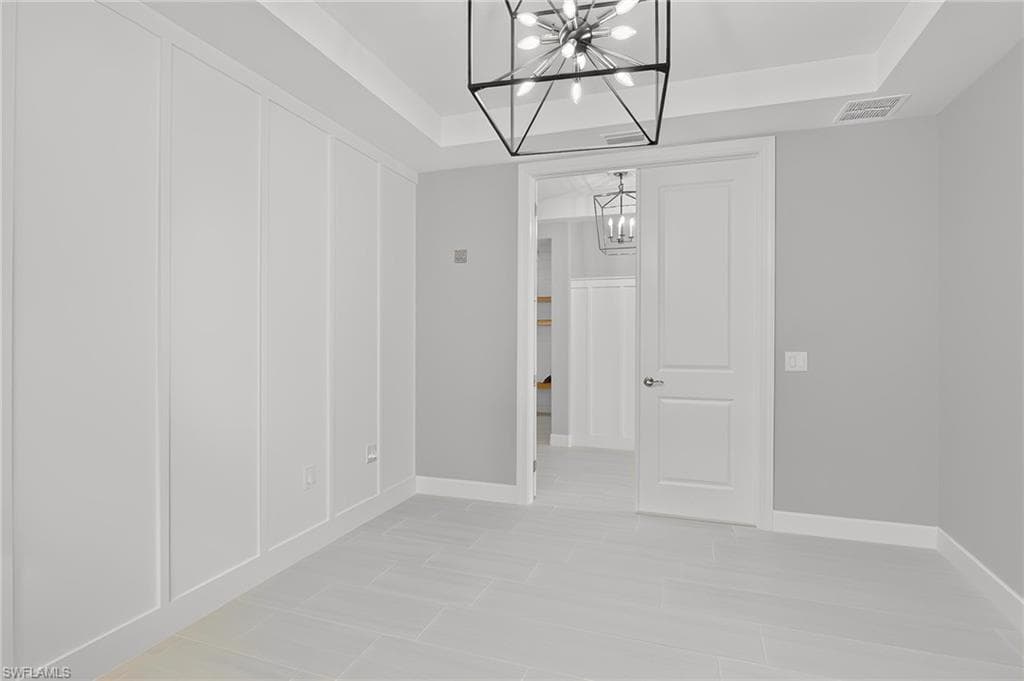 Interior space featuring plank wall paneling, a tray ceiling, and a modern geometric chandelier