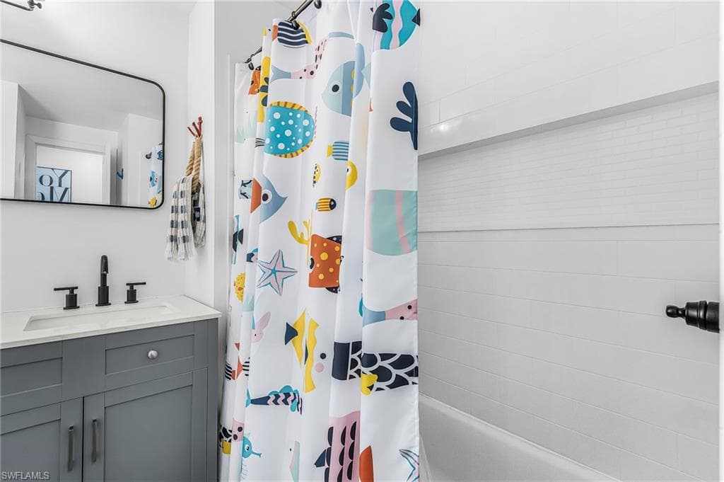 Bathroom featuring a white bathtub with subway tile surround, recessed shelf, and matte black fixture
