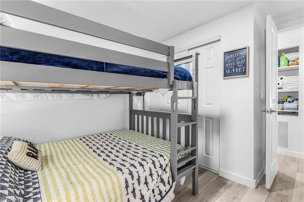 Room featuring a gray bunk bed with integrated ladder, white walls, and wood-finish flooring