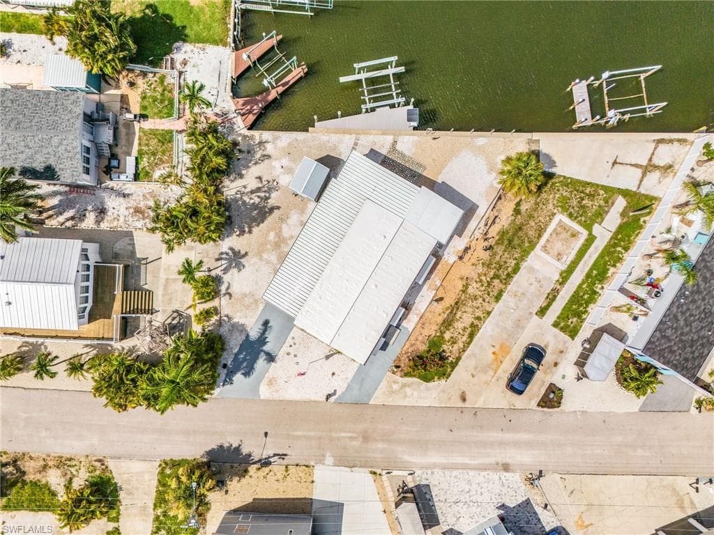 Waterfront property featuring a metal roof structure, a dock system, a gravel lot, and direct water access