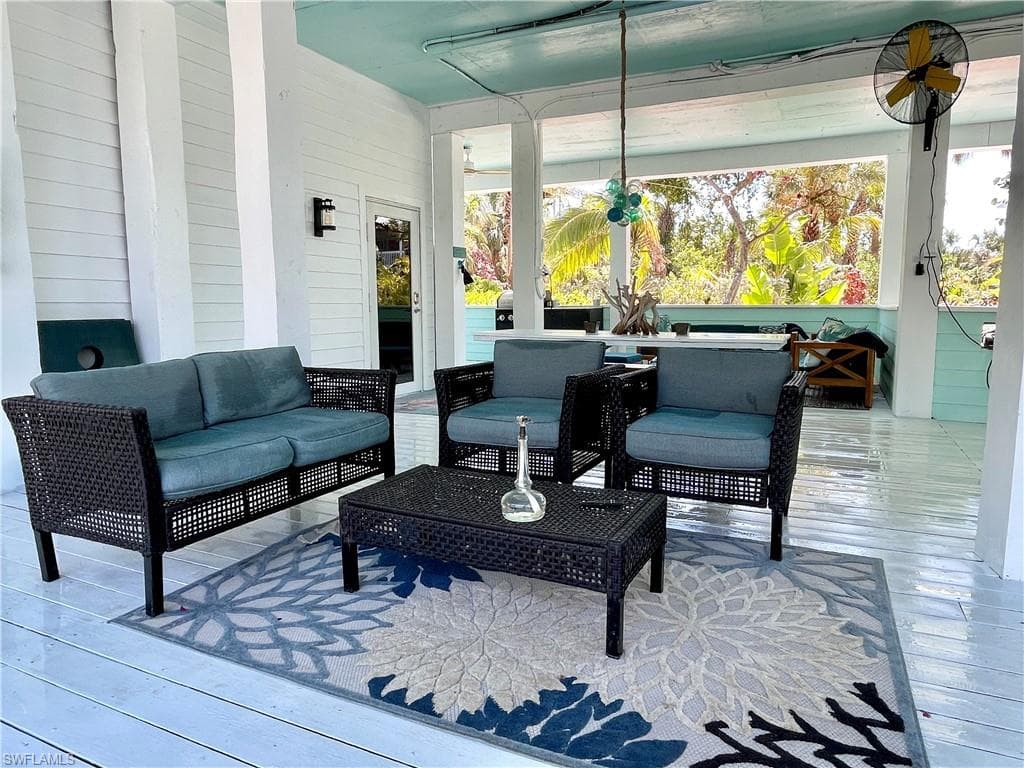 Covered outdoor patio featuring an outdoor TV, multiple lounge spaces, gas grill and refrigerator all adjacent to the pool.