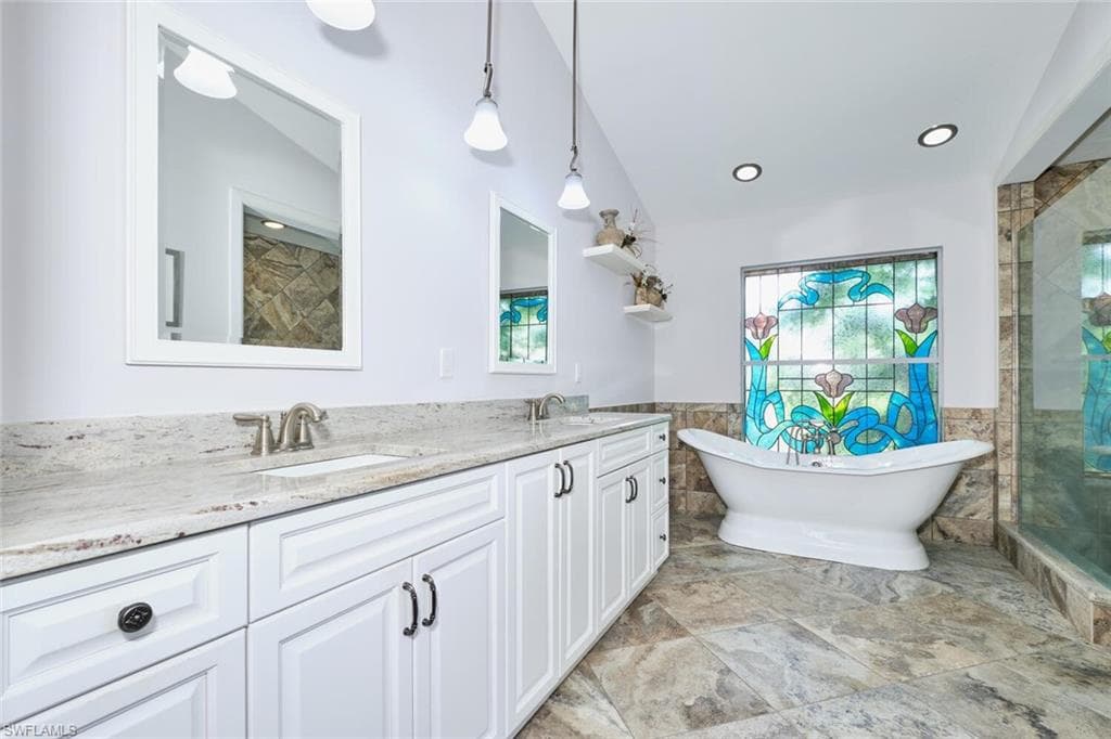 Full bath with tile floors, a soaking tub, double vanity, custom stained glass window and tiled shower.