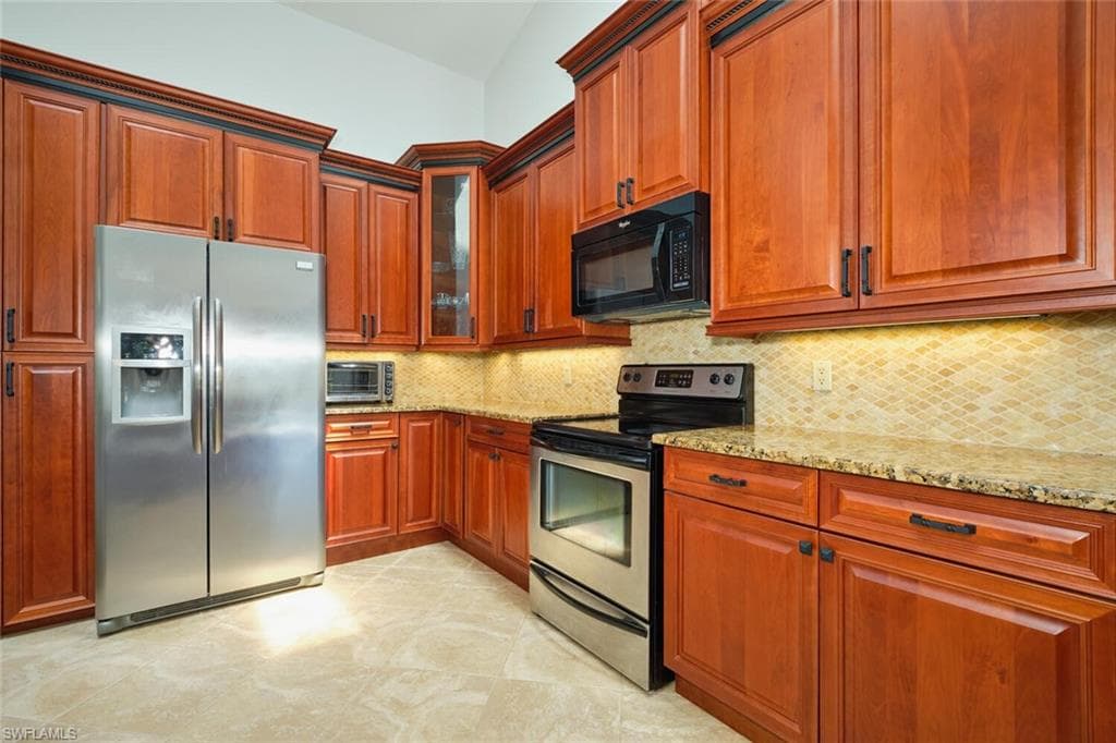 Kitchen featuring granite countertops, stainless steel appliances and decorative backsplash.