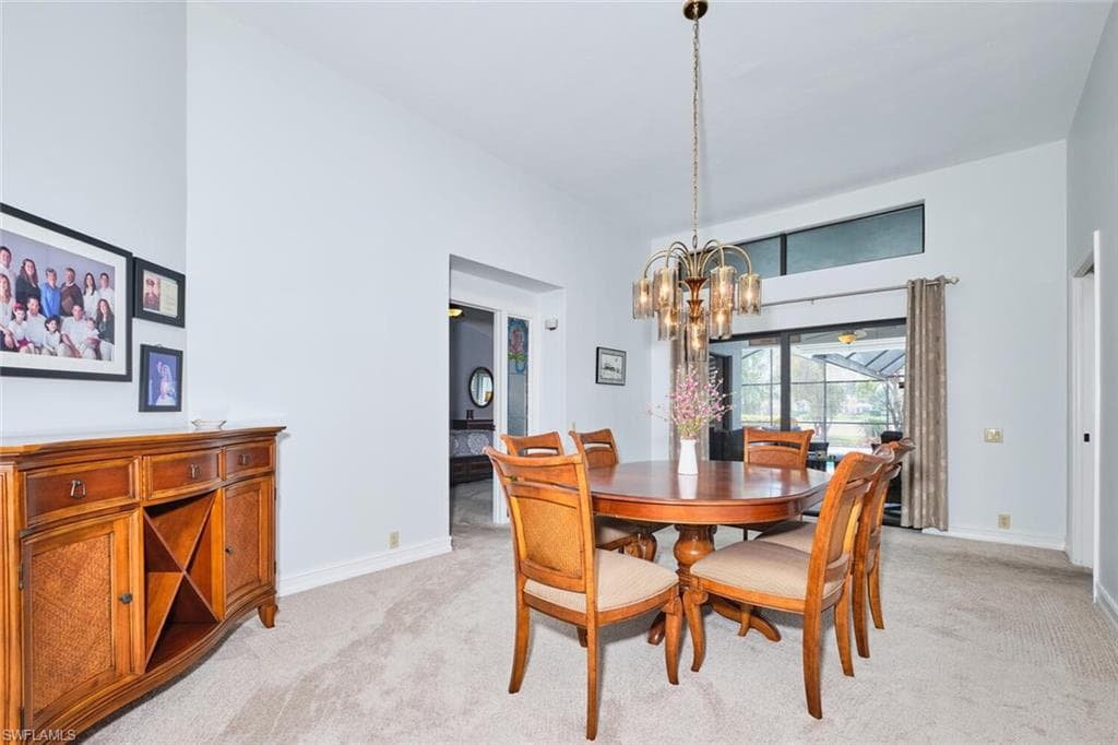 Dining room with an inviting chandelier, a towering ceiling and sliders out to the screened lanai.