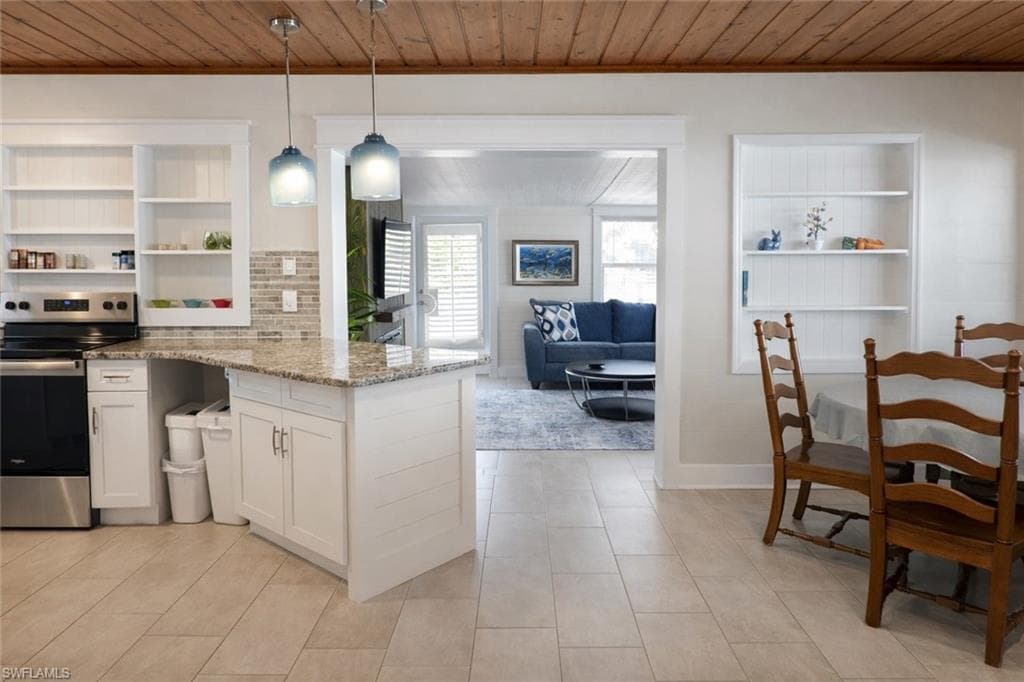Kitchen area featuring a wood-panel ceiling, pendant lighting, recessed shelving, granite-style countertops, and tile flooring