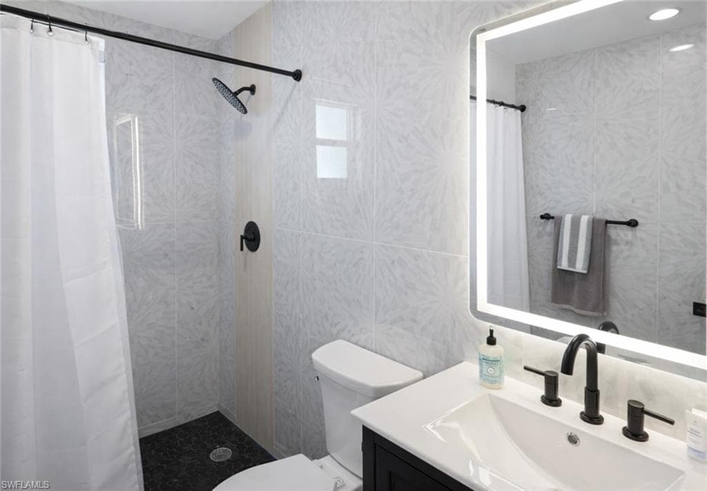 Contemporary bathroom featuring a black vanity with a white countertop and undermount sink, matte black faucet, and an illuminated mirror