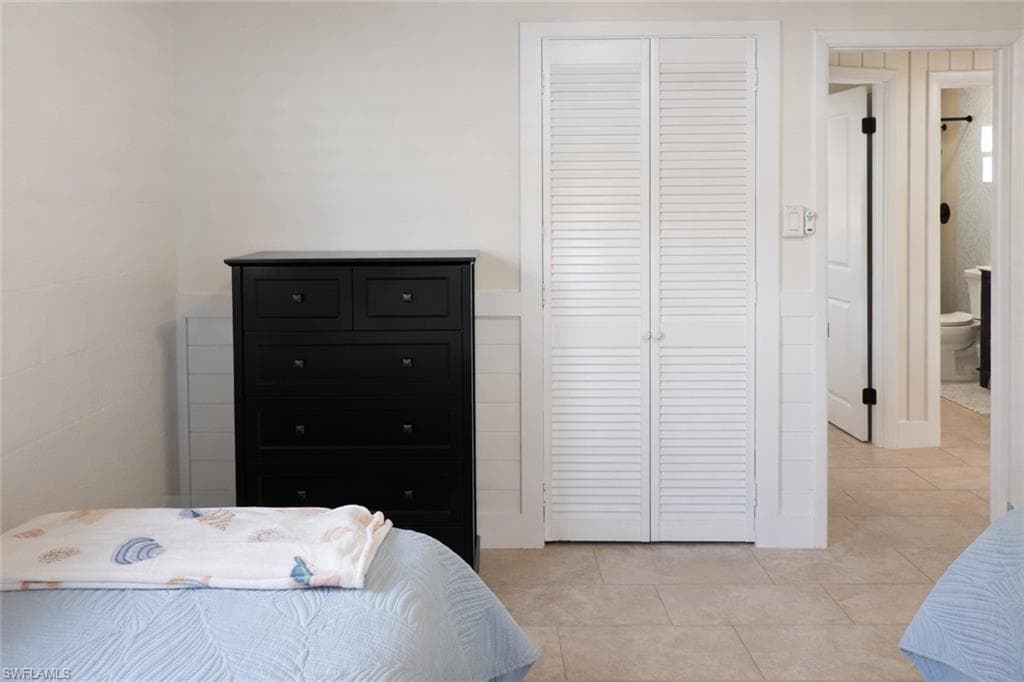 Light-toned tile flooring extends throughout this interior space, featuring white shiplap wainscoting and smooth white walls