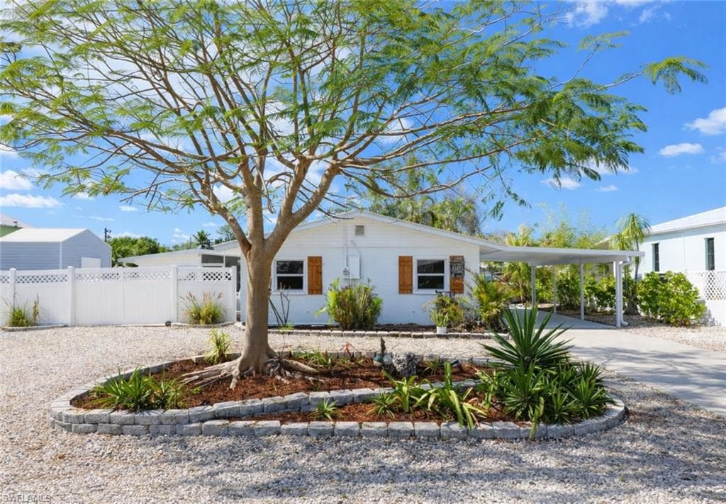 White single-story residence with a carport and gravel driveway