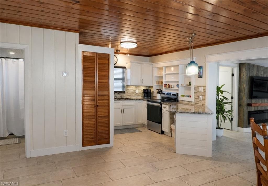 Open-concept kitchen featuring white cabinetry, stone countertops, a tiled backsplash, and stainless steel appliances
