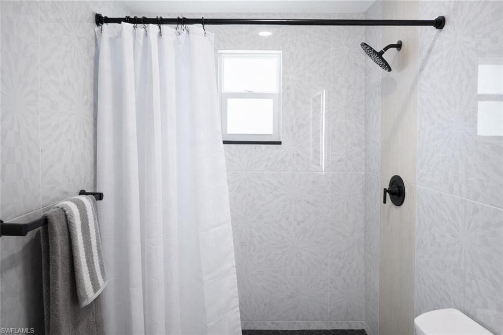 Shower area featuring contemporary patterned wall tiling, a matte black rainfall showerhead, and coordinating matte black fixtures