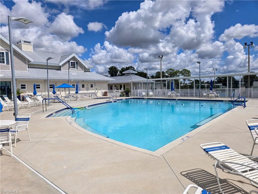 Spacious outdoor swimming pool with integrated stairs and handrails, surrounded by ample concrete decking