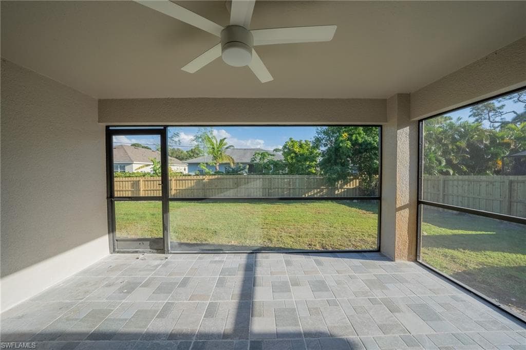 Screened lanai featuring large format rectangular floor tiles, a ceiling fan, and expansive views of the fenced backyard