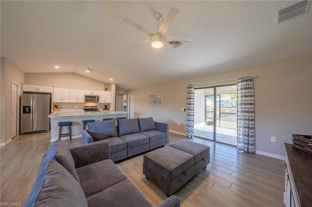 Open-concept living space featuring wood-finish flooring, a vaulted ceiling, and a ceiling fan