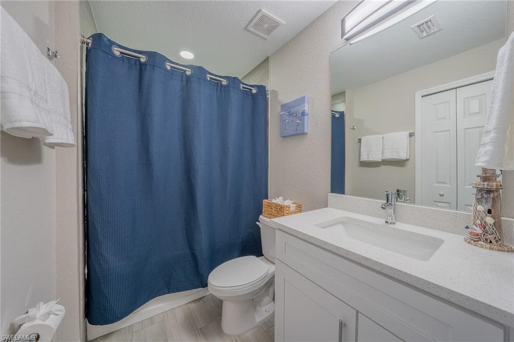 Bathroom featuring a white vanity with integrated sink, a light-colored countertop, and a shower with a privacy curtain