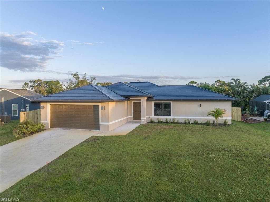 Stucco exterior featuring a dark tile roof, an attached two-car garage with a panel door, and a concrete driveway