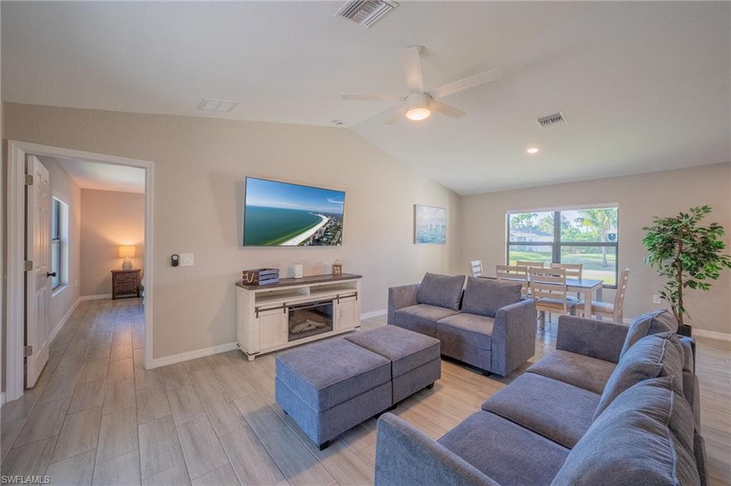 Vaulted ceiling living area featuring light-toned wood-finish flooring