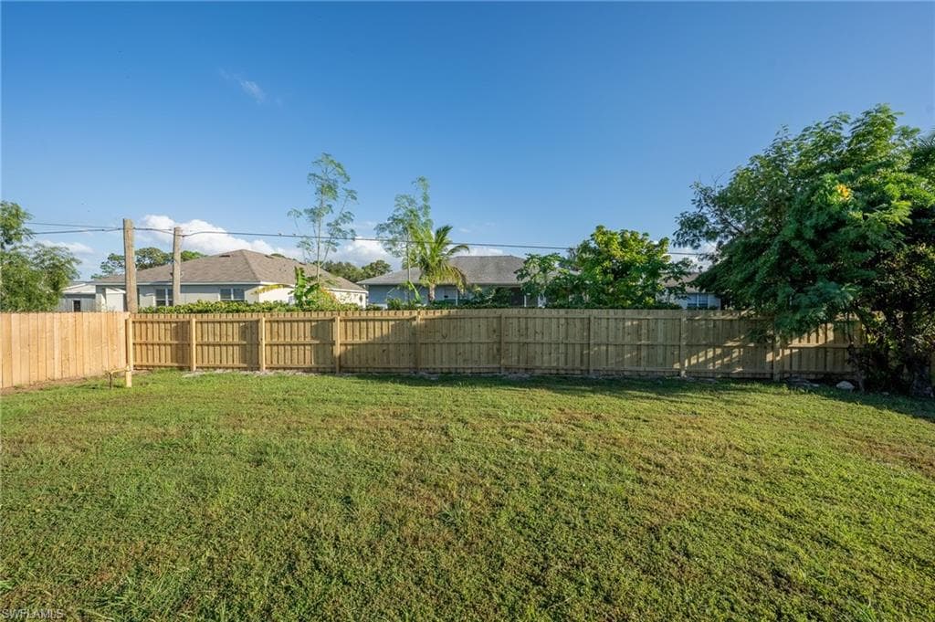 Expansive grassy yard area featuring a new wood privacy fence