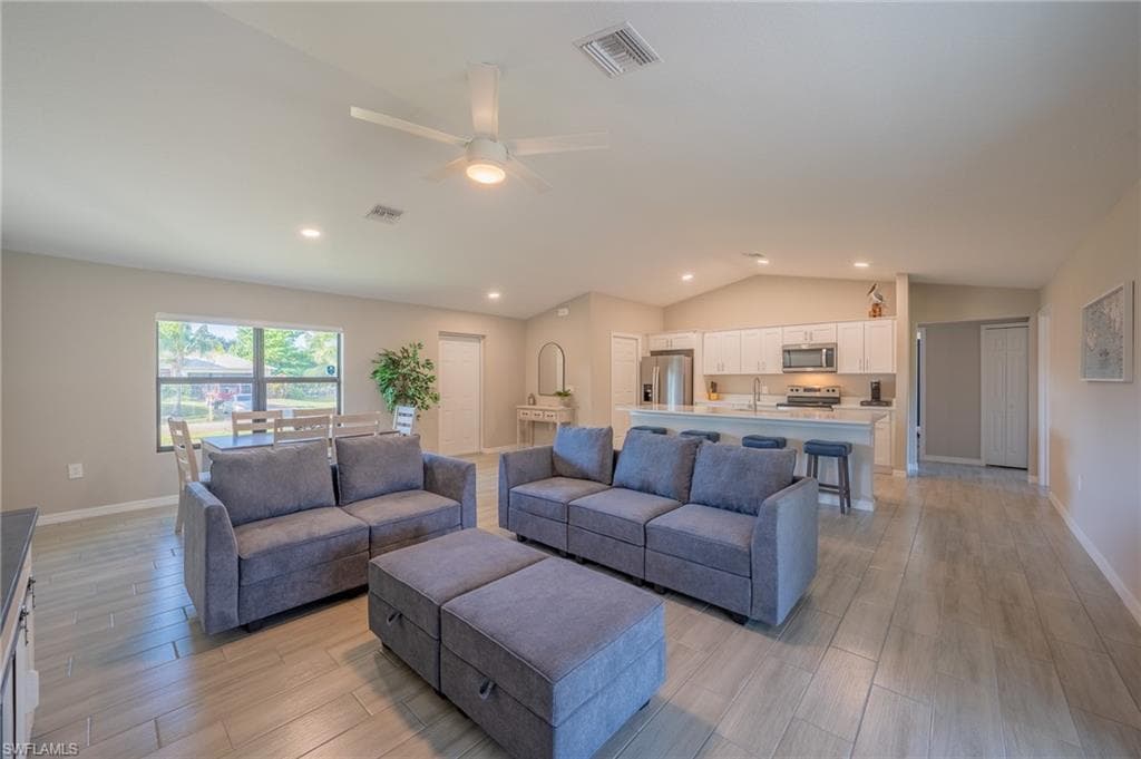 Open-concept living area featuring wood-finish tile flooring, recessed lighting, and a vaulted ceiling