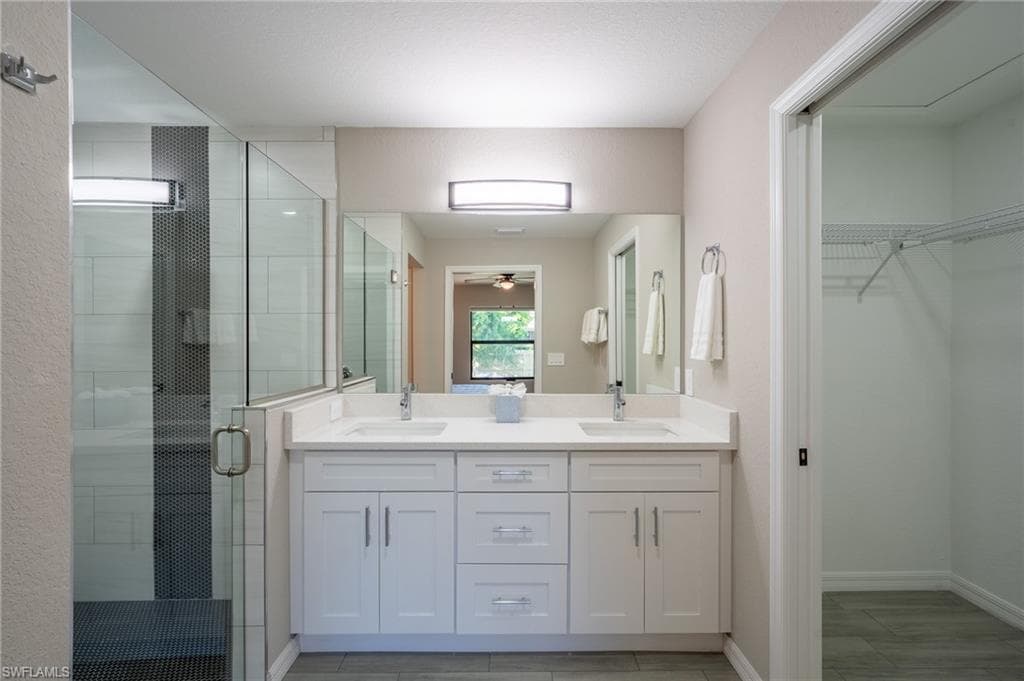 Dual vanity with white cabinetry, integrated sinks, and a large mirror