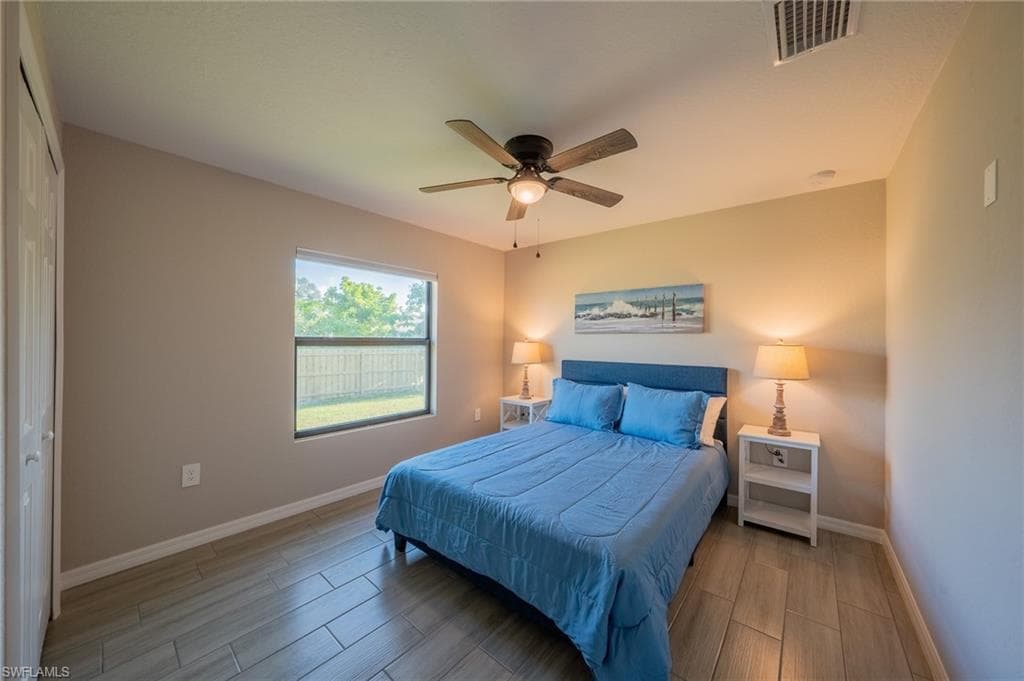 Bedroom featuring wood-finish flooring, a ceiling fan with integrated lighting, and a single window with exterior views