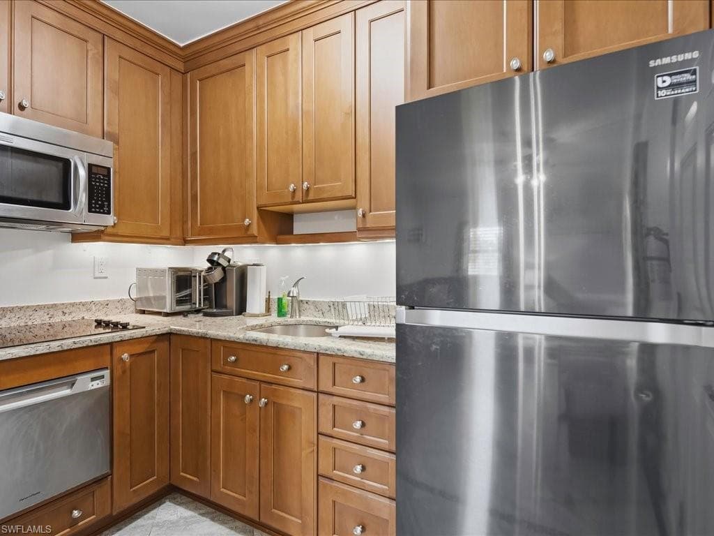 Kitchen featuring stainless steel appliances, wood cabinetry with crown molding, granite countertops, an undermount sink, and recessed lighting