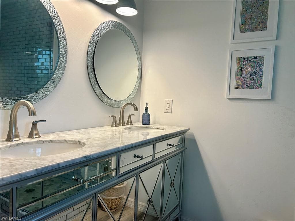 Double vanity featuring a light-toned countertop, dual undermount sinks with brushed nickel faucets, and mirrored cabinetry