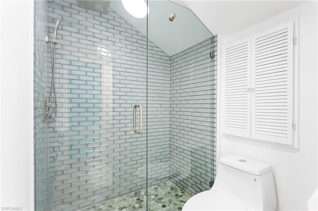 Glass-enclosed shower with subway tile surround and pebble-finish flooring