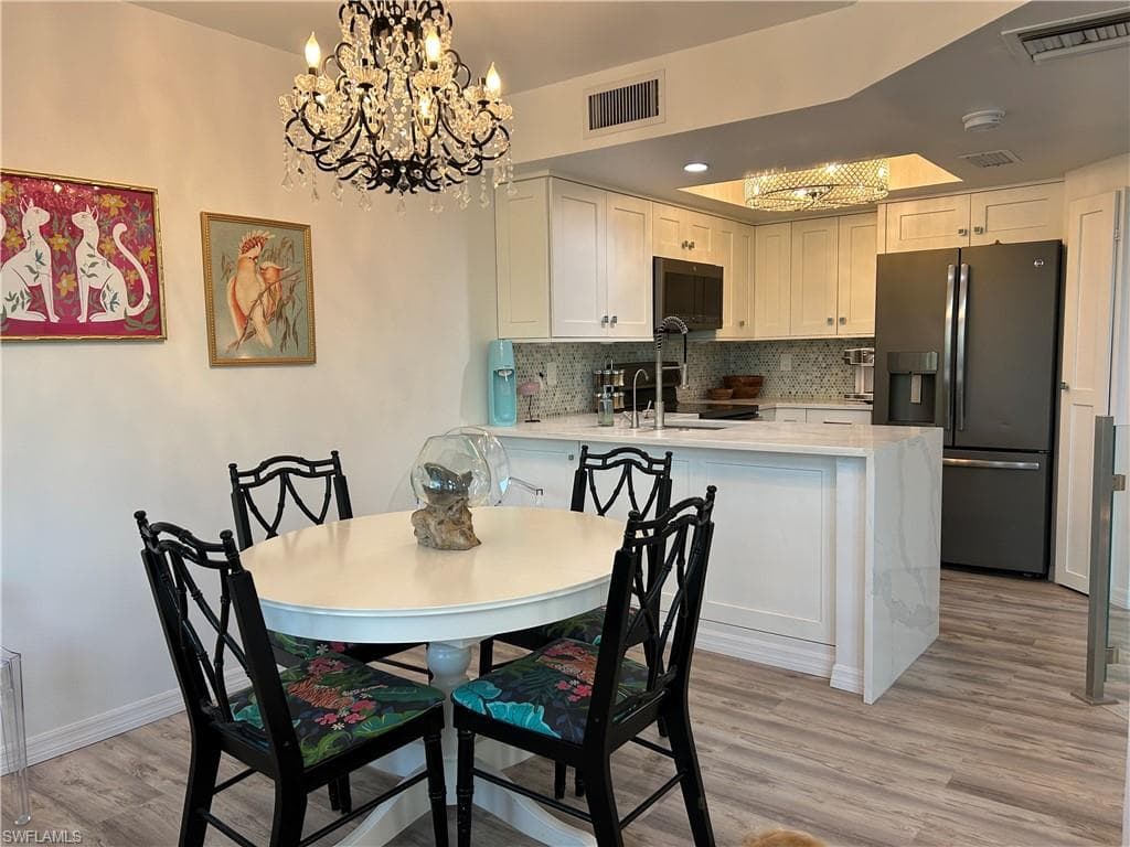 Open-concept kitchen featuring white cabinetry, a large refrigerator, and a kitchen island with seating