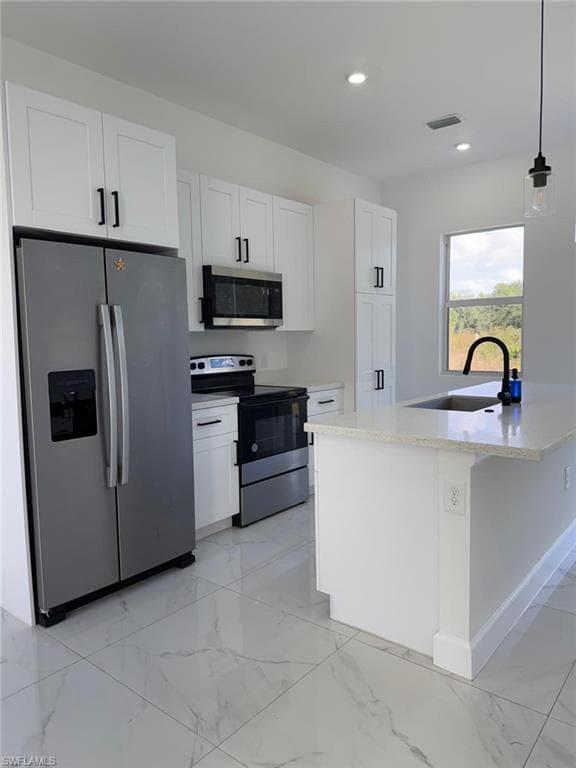 Kitchen featuring appliances with stainless steel finishes, light marble finish floors, white cabinetry, light stone counters, and recessed lighting