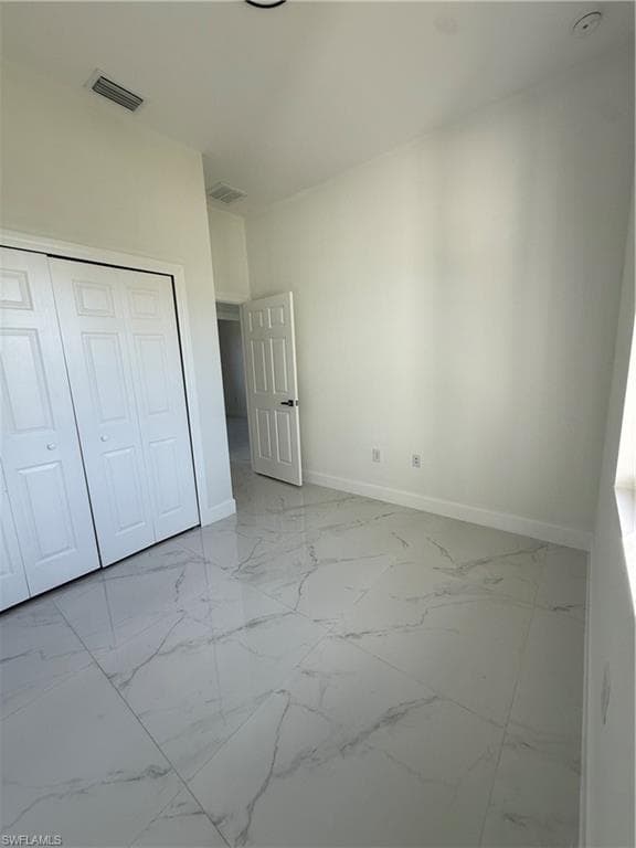 Unfurnished bedroom featuring light marble finish flooring and a closet