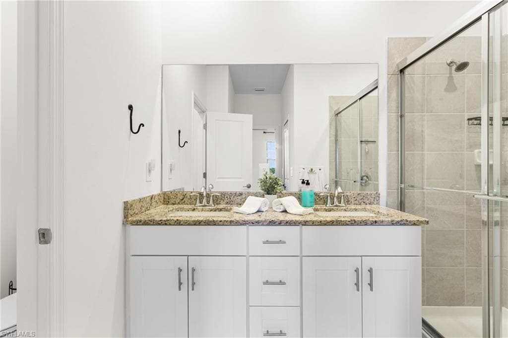 The ensuite bath offers granite countertops, dual sinks, and a glass-enclosed walk-in shower