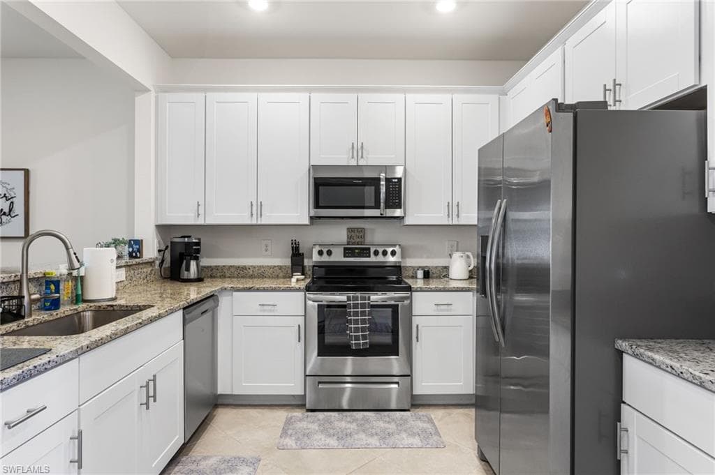The spacious kitchen boasts granite countertops, stainless steel appliances, a deep sink, and white shaker cabinets