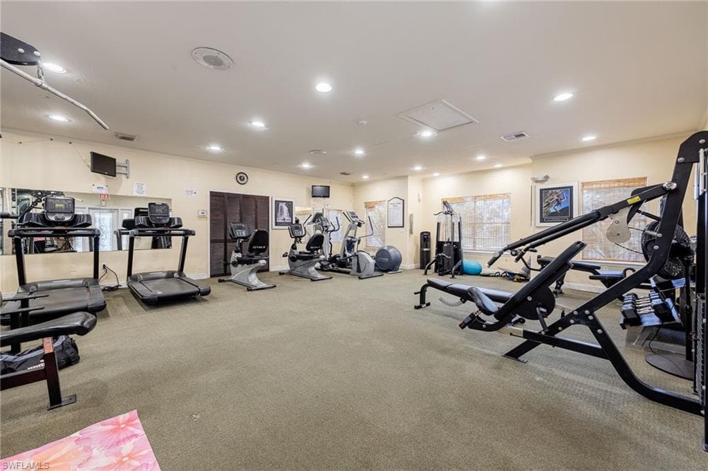 Fitness room featuring carpeted flooring, recessed lighting, wall-mounted mirrors, and multiple exercise machines