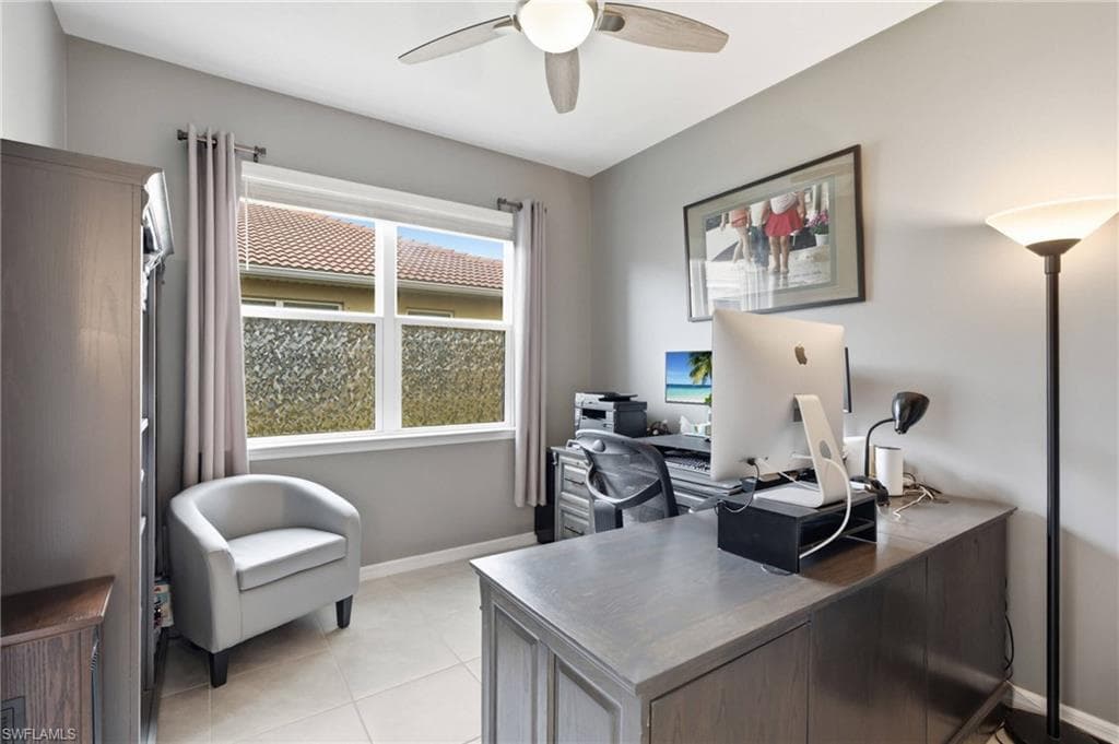 Versatile room featuring a large window with privacy film, tile flooring, and a ceiling fan