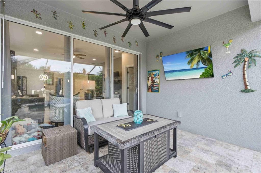 Covered patio featuring a ceiling fan, wall-mounted television, and stone-look tile flooring