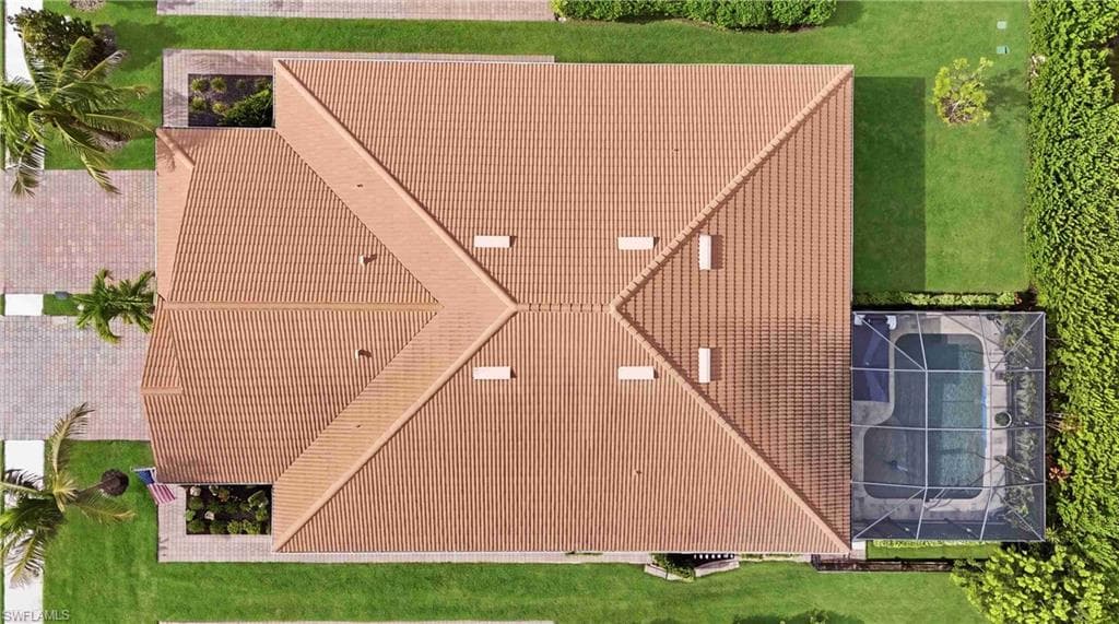 Terracotta-style tile roof and screened pool area complement the meticulously landscaped grounds
