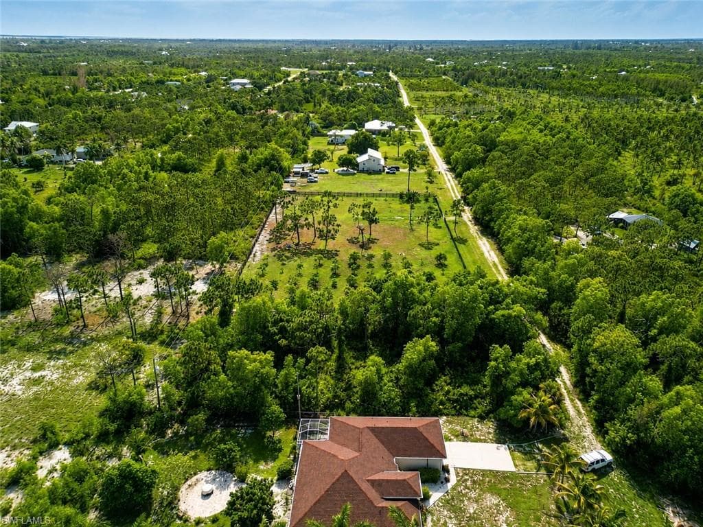 Expansive aerial perspective showcasing a property with a distinct red-tiled roof and a light-colored driveway