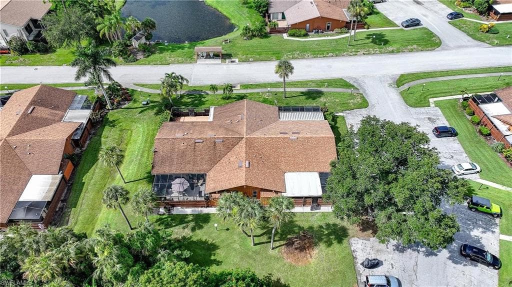 Property featuring a brown shingle roof, a screened patio, and mature landscaping