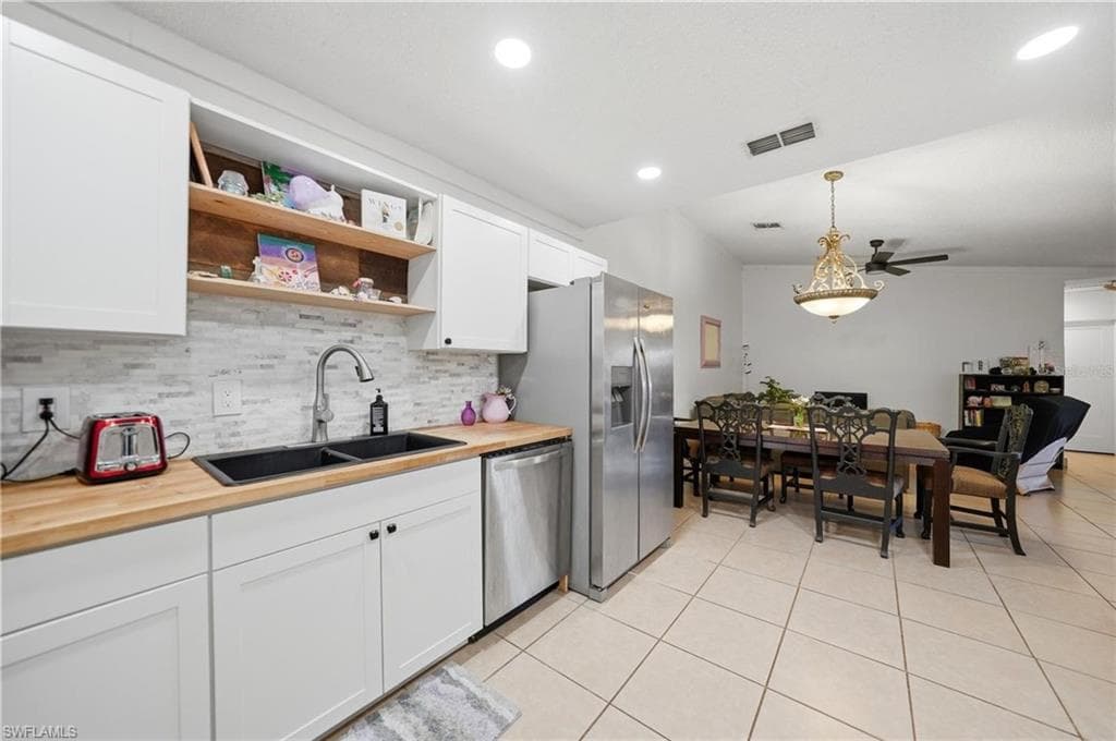 Kitchen featuring white cabinetry, butcher block countertops, and a subway tile backsplash