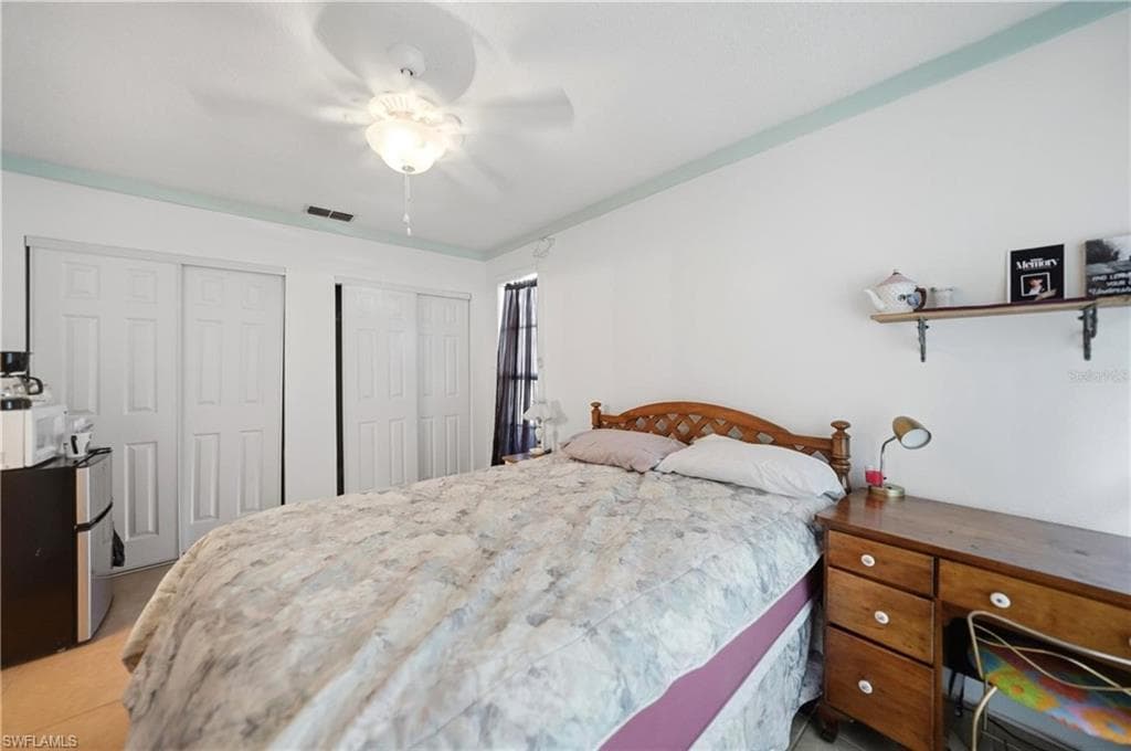 Bedroom featuring a wooden bed frame, ceiling fan with light fixture, and light-colored flooring