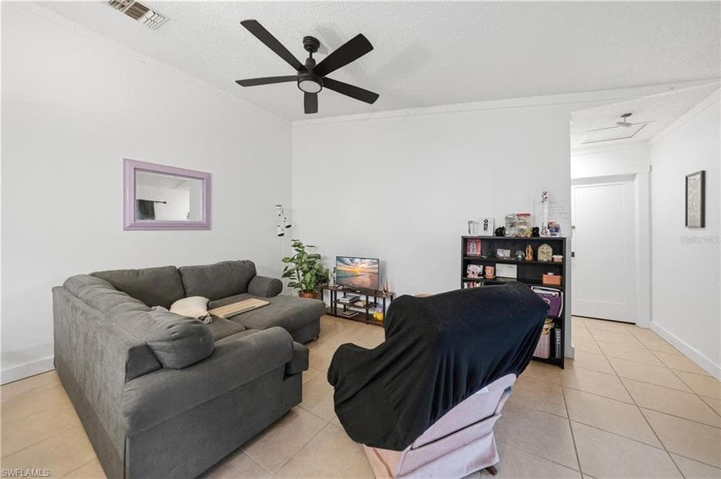 Living area featuring tile flooring, a black ceiling fan, and white walls