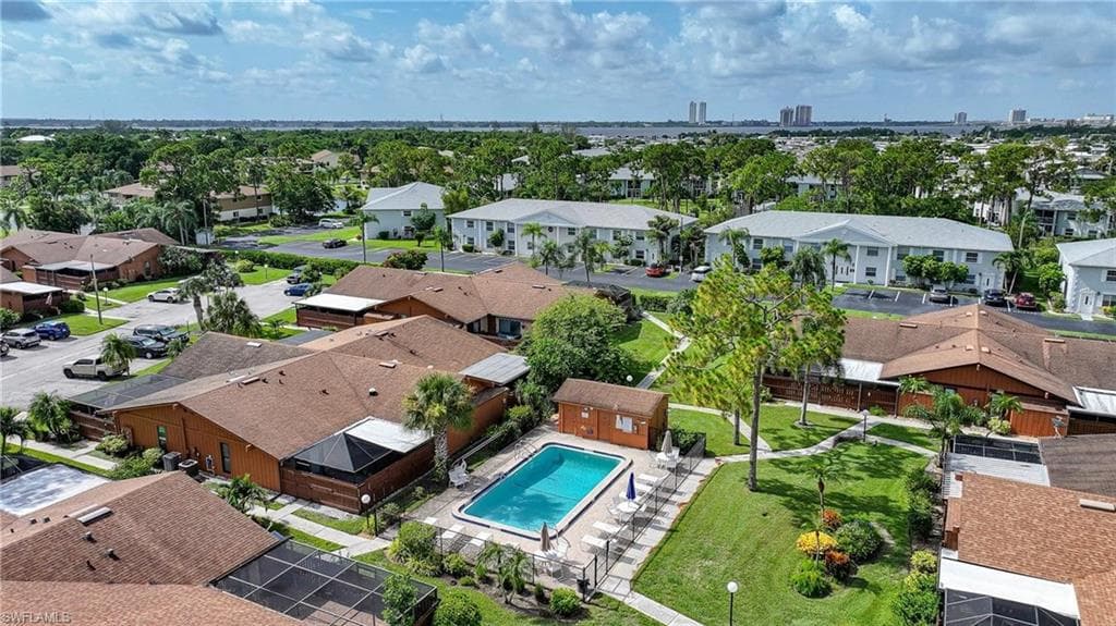 Community pool with surrounding patio, fenced perimeter, and nearby manicured green space