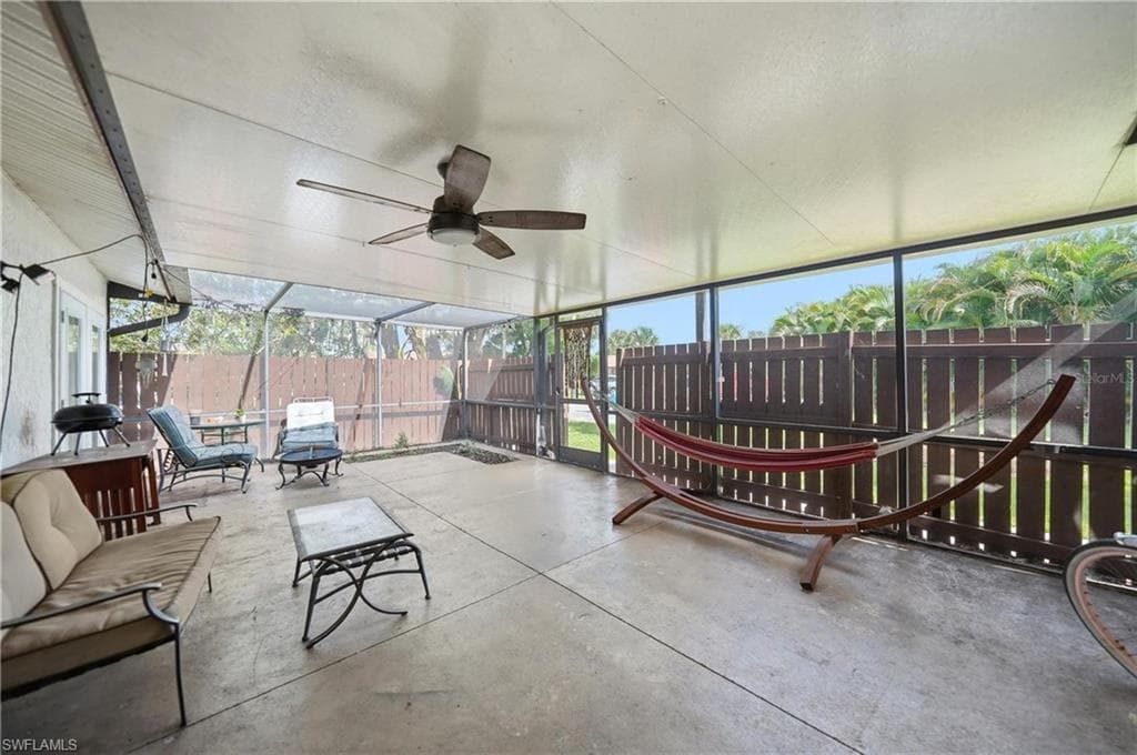 Screened patio featuring a ceiling fan, concrete flooring, and a privacy fence