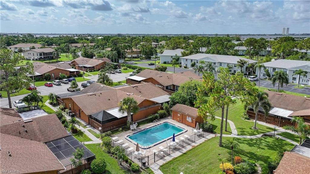 Community amenities featuring an outdoor swimming pool, surrounding lounge area, and a green space with mature trees